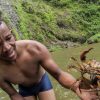 Ein Mann hält eine Krabbe vor einem Salto La Jalda (Wandern und Schwimmen).